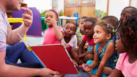 Erzieher sitzt vor einer Kindergartengruppe
