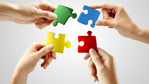 Vier Hände halten Puzzleteile