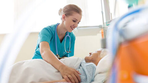 Pflegerin ist einer bettlägrigen Senioren behilflich
