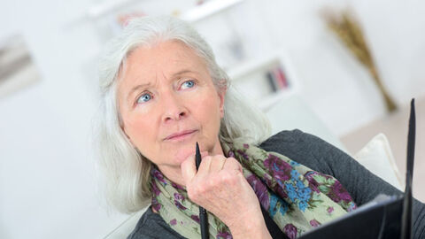 Seniorin schaut nachdenklich in die Ferne