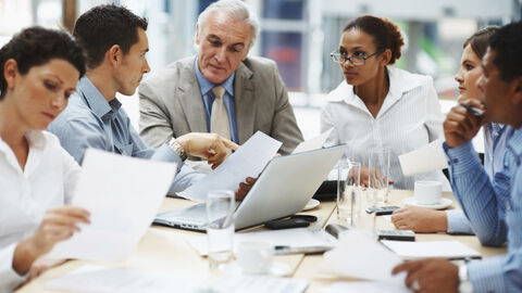 Meeting an einem Konferenztisch, Männer und Frauen verschiedener Nationalität