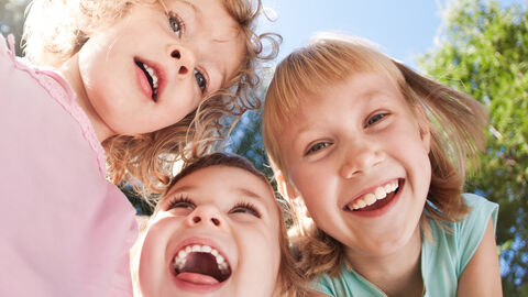 3 fröhliche Kinder lachen in die Kamera