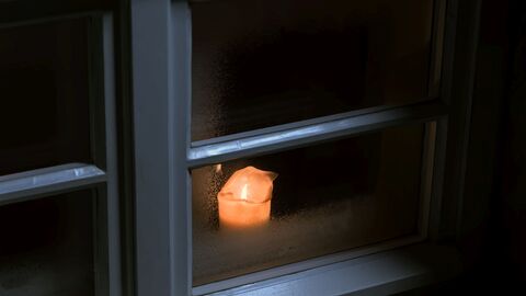 Brennende Kerze im Fenster