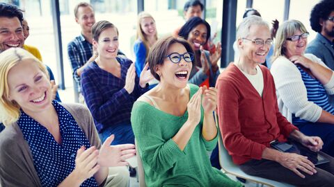 Austausch und Miteinander Fröhlich lächelnde Menschen sitzen auf Stühlen in einem sonnigen Raum und applaudieren