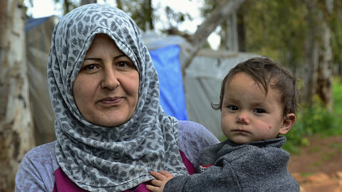 Mutter hält ihr Kind in einem Flüchtlingscamp auf dem Arm
