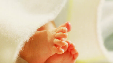 Foto zeigt Babyfüße im Sonnenlicht auf einer weißen Decke und das Logo der Bundesstiftung Frühe Hilfen