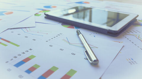 iPad, Stift und mit Diagrammen bedrucke Papiere liegen auf einem Tisch