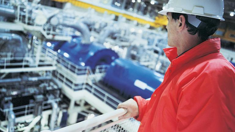 Arbeiter in Schutzkleidung schaut in Maschinenhalle