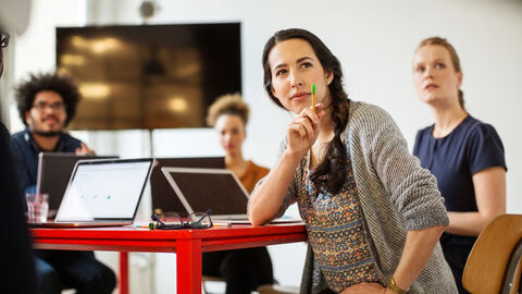 Junge Menschen sitzen am Tisch, vor jeder Person befindet sich ein Laptop