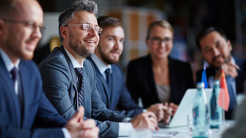 Männer und Frauen in Geschäftskleidung in einer Konferen Männer und Frauen in Geschäftskleidung in einer Konferenz
