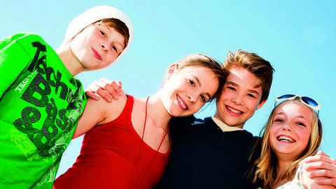 Jugendliche lächeln vor einem blauen Himmel in die Kamera