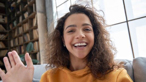 Junge Frau winkt freundlich in die Kamera Junge Frau winkt freundlich in die Kamera