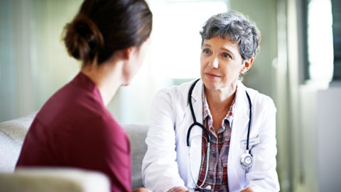 Aufnahme einer mitfühlenden Ärztin, die eine junge Frau im Wartezimmer eines Krankenhauses tröstet