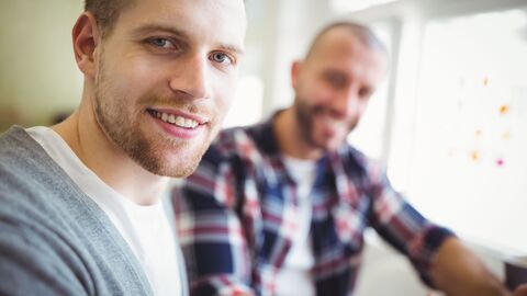 Kollegen im Büro tauschen sich aus, ein Mann sitzt im Rollstuhl