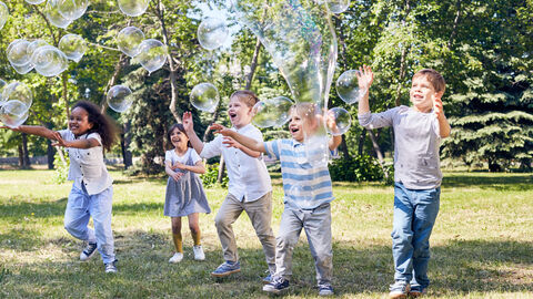 Eine Gruppe Kinder im Park haben Spaß mit großen Seifenblasen
