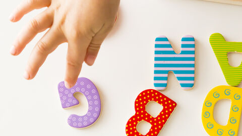 Eine Kinderhand ordnet Buchstaben 