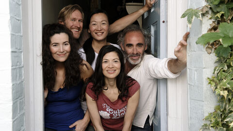 Eine Gruppe Menschen steht lächelnd in einer geöffneten Tür