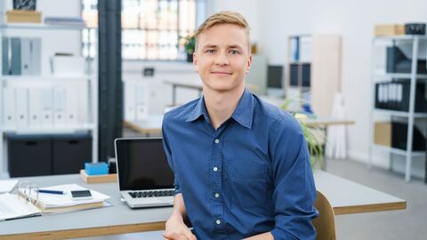 Junger Praktikant sitzt entspannt am PC-Arbeitsplatz