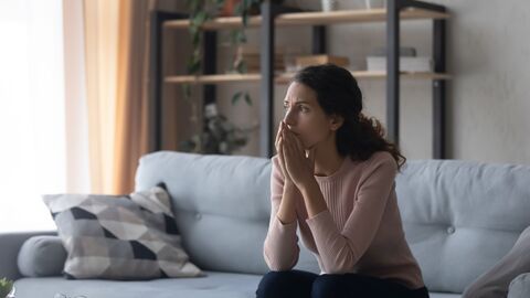 Nachdenkliche junge Frau Nachdenkliche junge Frau sitzt auf Couch