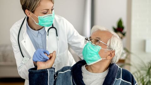 Senior sitzt im Bademantel im Rollstuhl