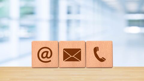 Holzklötze mit E-Mail-, Post- und Telefonsymbolen mit Bürohintergrund