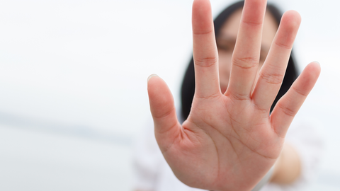 Eine Frau hält eine Hand zur Abwehr hoch