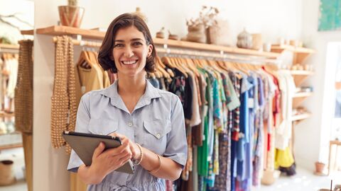 Eine junge Frau in einem Modegeschäft, sie überprüft mit einem Tablett den Warenbestand