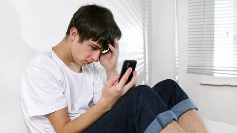 Junger trauriger Mann schaut in sein Smartphone