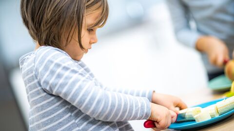 Gesundes Essen, Situation in einer Küche, ein Mädchen schneidet eine Banane
