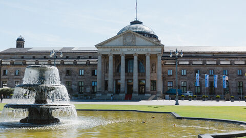 Ansicht des Kurhaus Wiesbaden, ein Brunnen im Vordergrund.