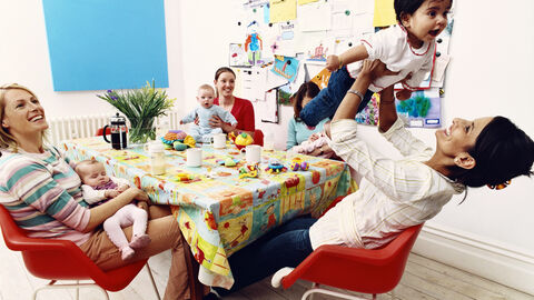 Frauen mit Kinder sitzen um einen Tisch 