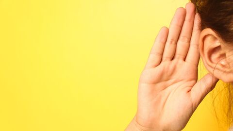 Eine Hand am Ohr um besser zu hören