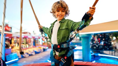 Kleiner Junge steht gesichert auf einem Trampolin