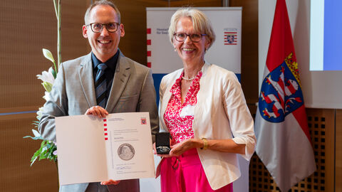 Sozialminister Klose überreicht die Urkunde an Gerda Holz