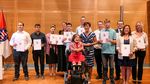 Gruppenfoto mit Staatsministerin Puttrich und der Landesbeauftragten Esser vor einem Halbkreis aus neuen Landesbeschäftigten.
