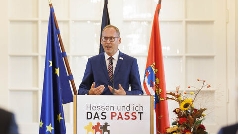 Einbürgerungsfeier 2023 Integrationsminister Kai Klose am Rednerpult der Einbürgerungsfeier. Im Hintergrund die Flaggen von Europa, Deutschland und Hessen.