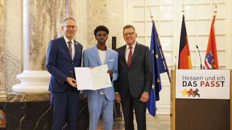 Einbürgerungsfeier 2023: Gebeyehu Filfil Minister Klose und Staatssekretär Sauer mit Gebeyehu Filfil bei der Einbürgerungsfeier. Filfil hält die Einbürgerungsurkunde in den Händen.