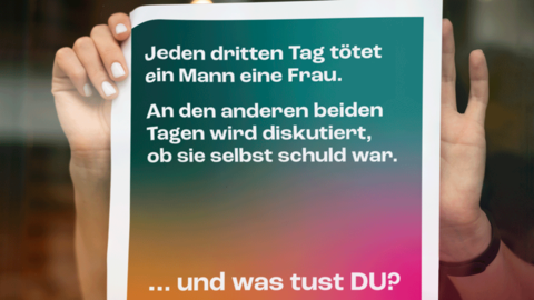Aktionsplakat mit dem Motiv „FEMIZID“ Schaufensterscheibe eines Geschäfts. Hinter der Scheibe bringen zwei Hände einer Frau gerade das Aktionsplakat mit dem Motiv „FEMIZID“ an
