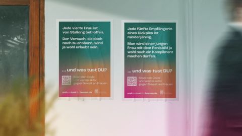 Plakate mit den Motiven „GEWALT GEGEN FRAUEN“ und „STALKING“ Blick von innen an eine Glastür mit zwei Plakaten. Die Motive „GEWALT GEGEN FRAUEN“ und „STALKING“ sind zu sehen. Vor der Tür geht gerade eine Person unscharf nach links aus dem Bild