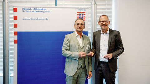 Preisträger Helmut Ruppel steht neben Sozialminister Klose. Beide lächeln in die Kamera.