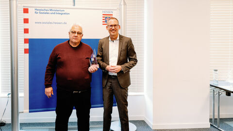 Preisträger Alfred Brüstle steht neben Sozialminister Klose. Beide lächeln in die Kamera.