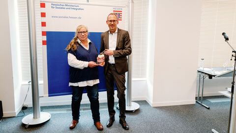 Preisträgerin Simone Schafnitzel neben Sozialminister Klose. Beide schauen in die Kamera.