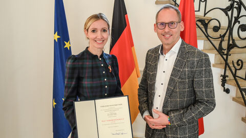 Prof. Sandra Ciesek und Sozialminister Kai Klose posieren vor der Kamera und lächeln.