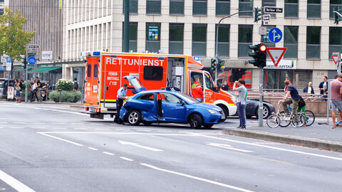 Unfallsituation an einer Straßenkreuzung. Zu sehen ist ein Rettungswagen und ein PKW mit Unfallschaden
