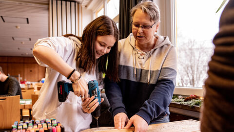 Frau hilft Mädchen dabei etwas zu bohren