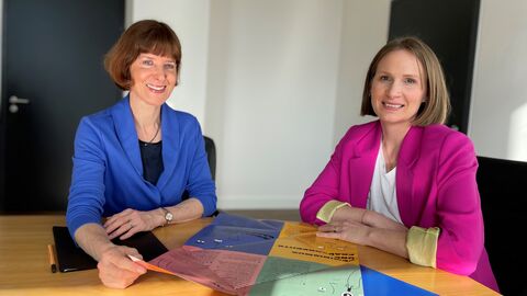 Ministerin Hofmann (links) sitzt gemeinsam mit Miriam Zeleke an einem Tisch. Vor ihnen sind Unterlagen ausgebreitet.