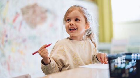 Kleines Mädchen zeichnet mit Markern im Kindergarten