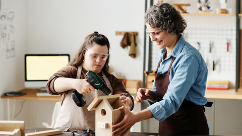 In einer Behindertenwerkstatt baut eine junge Frau ein Vogelhaus 