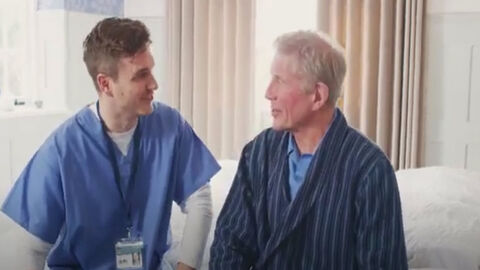 Junger Krankenpfleger spricht mit Patient