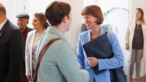Integrationsministerin Heike Hofmann schüttelt die Hand einer Frau und lächelt dabei.